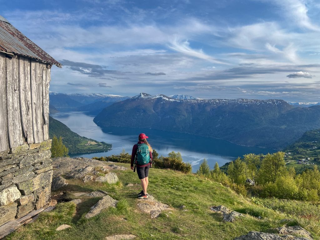 Woman standing above Lustrafjord near Svarthiller Fjellgård on the Molden hike, overlooking the fjord landscape