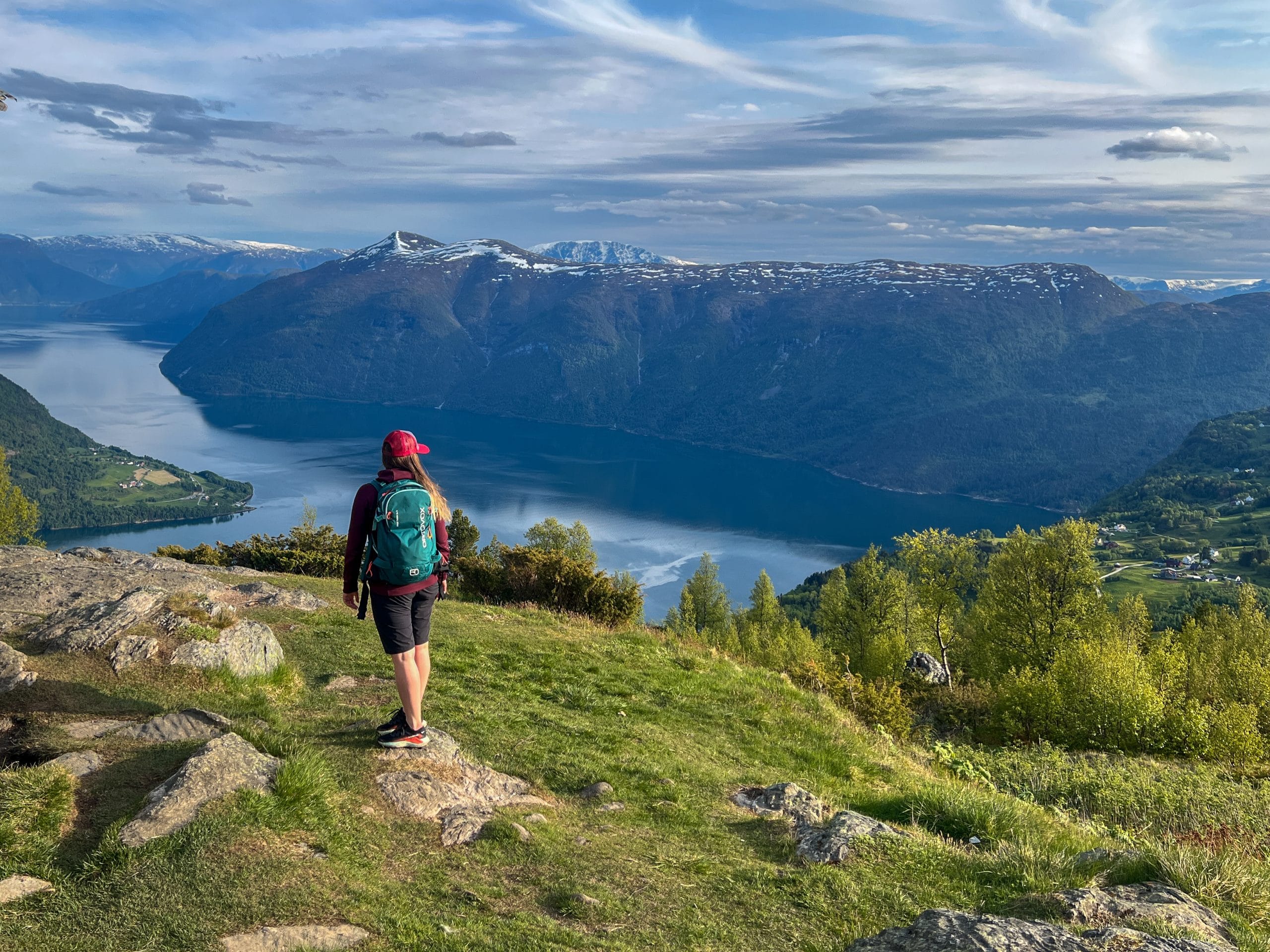 Woman standing above Lustrafjord on the Molden hike, overlooking the fjord on a sunny day