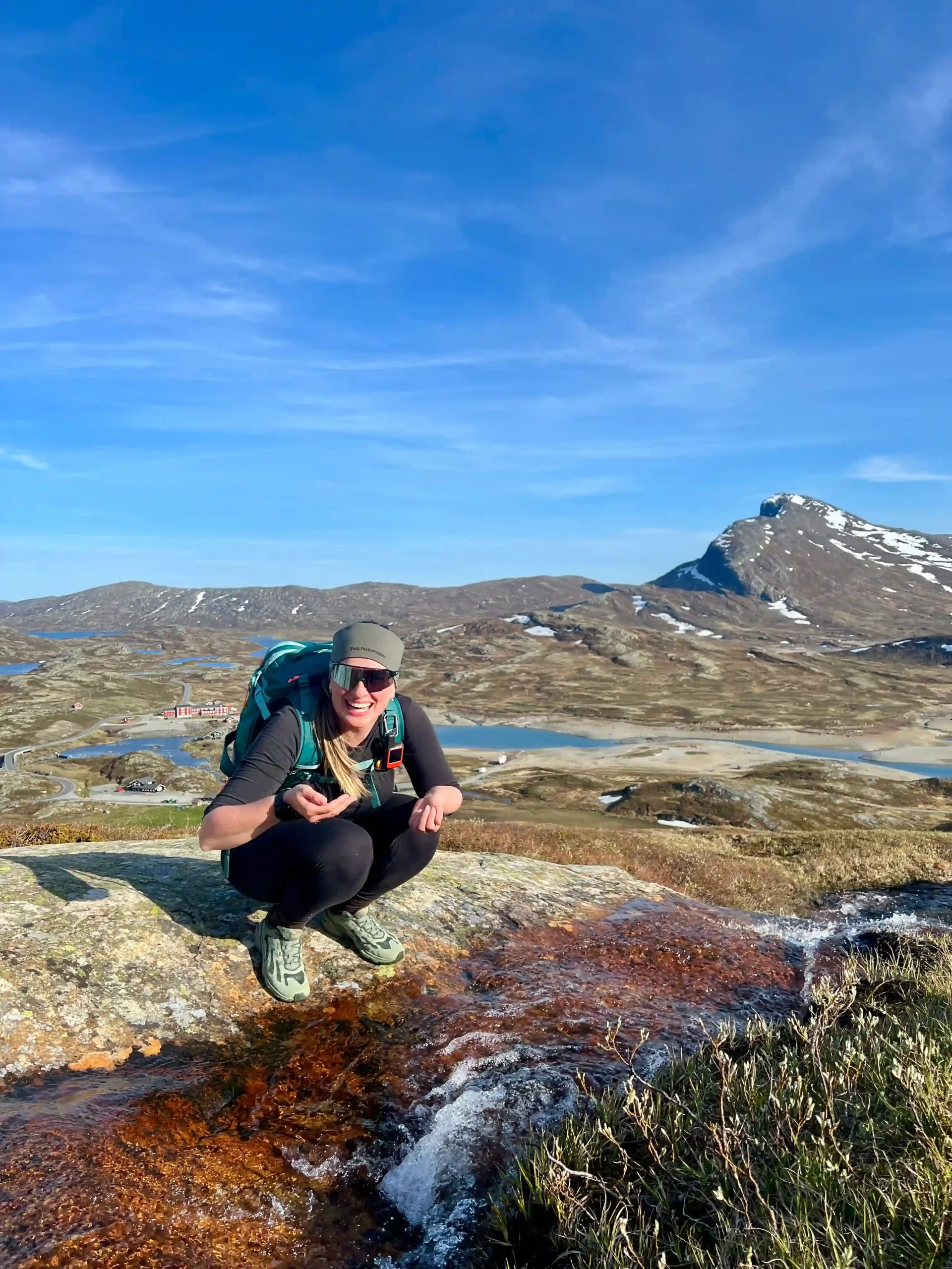 About Jana drinking from a mountain stream during a hike in Norway