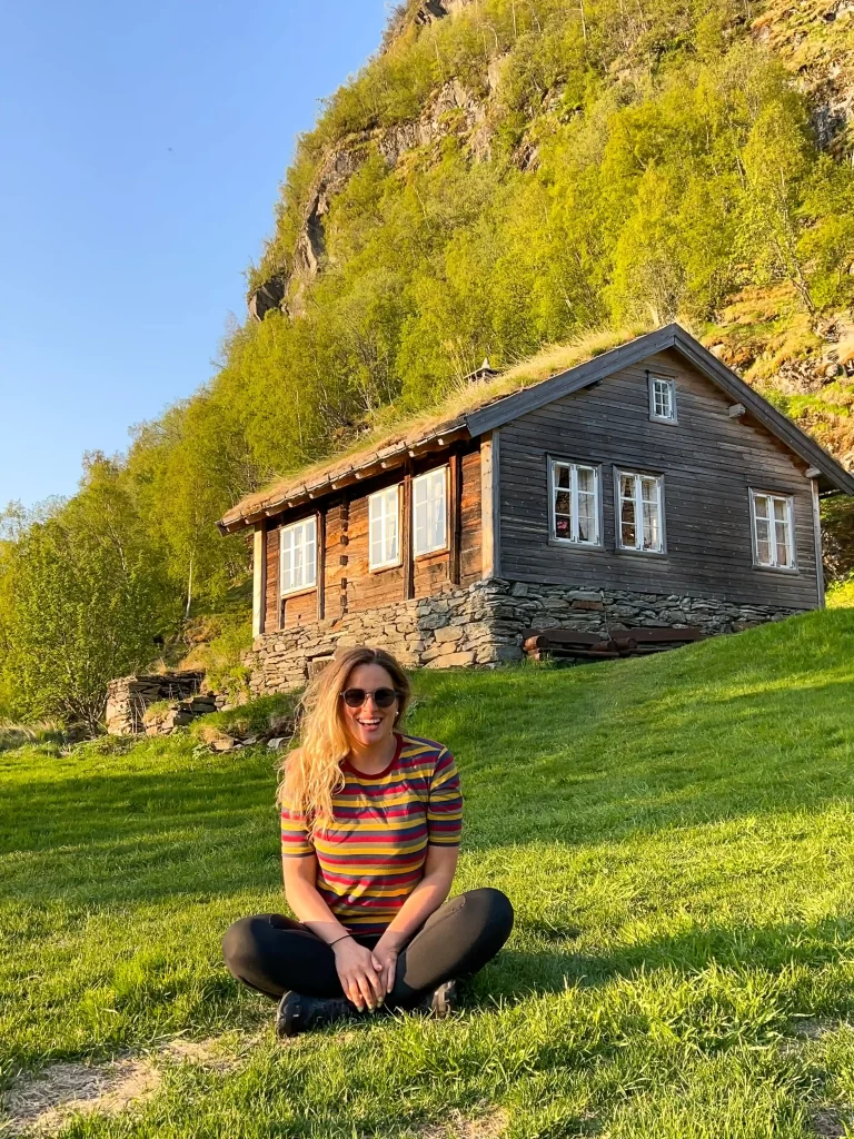 Consultations Woman sitting on grass in front of a traditional cabin in Norway