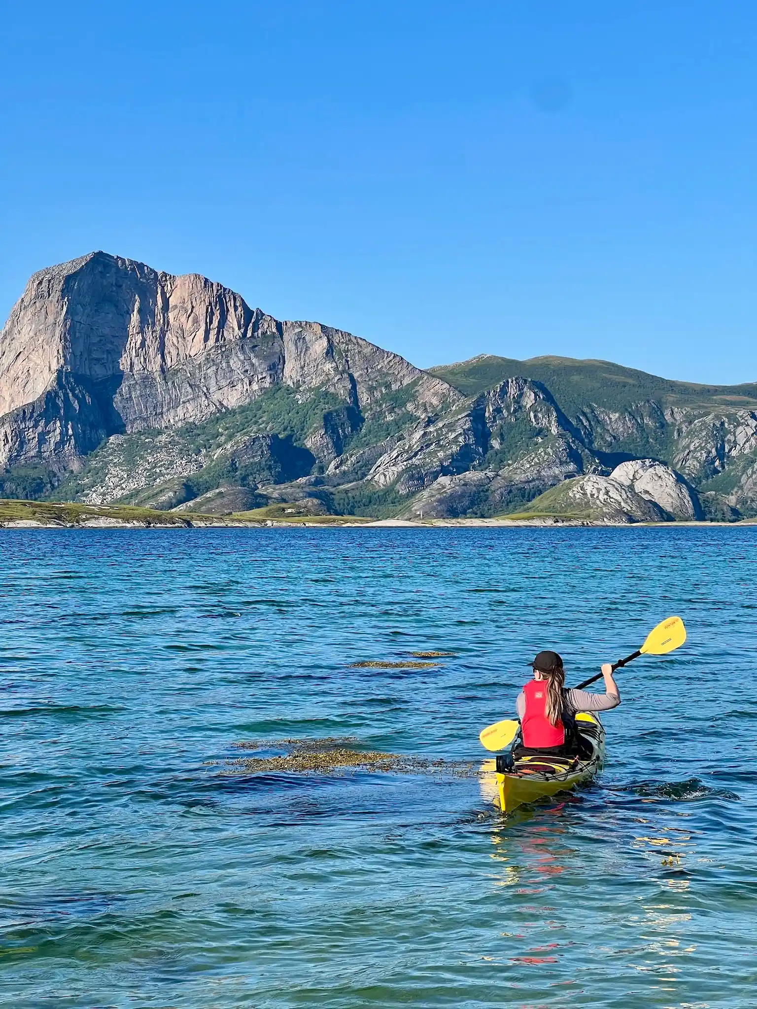 Woman kayaking along a quiet coastal landscape in Norway