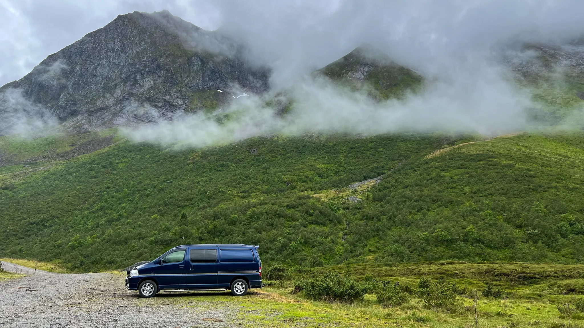 Planning a Norway road trip with a small van parked in front of moody mountains in Norway