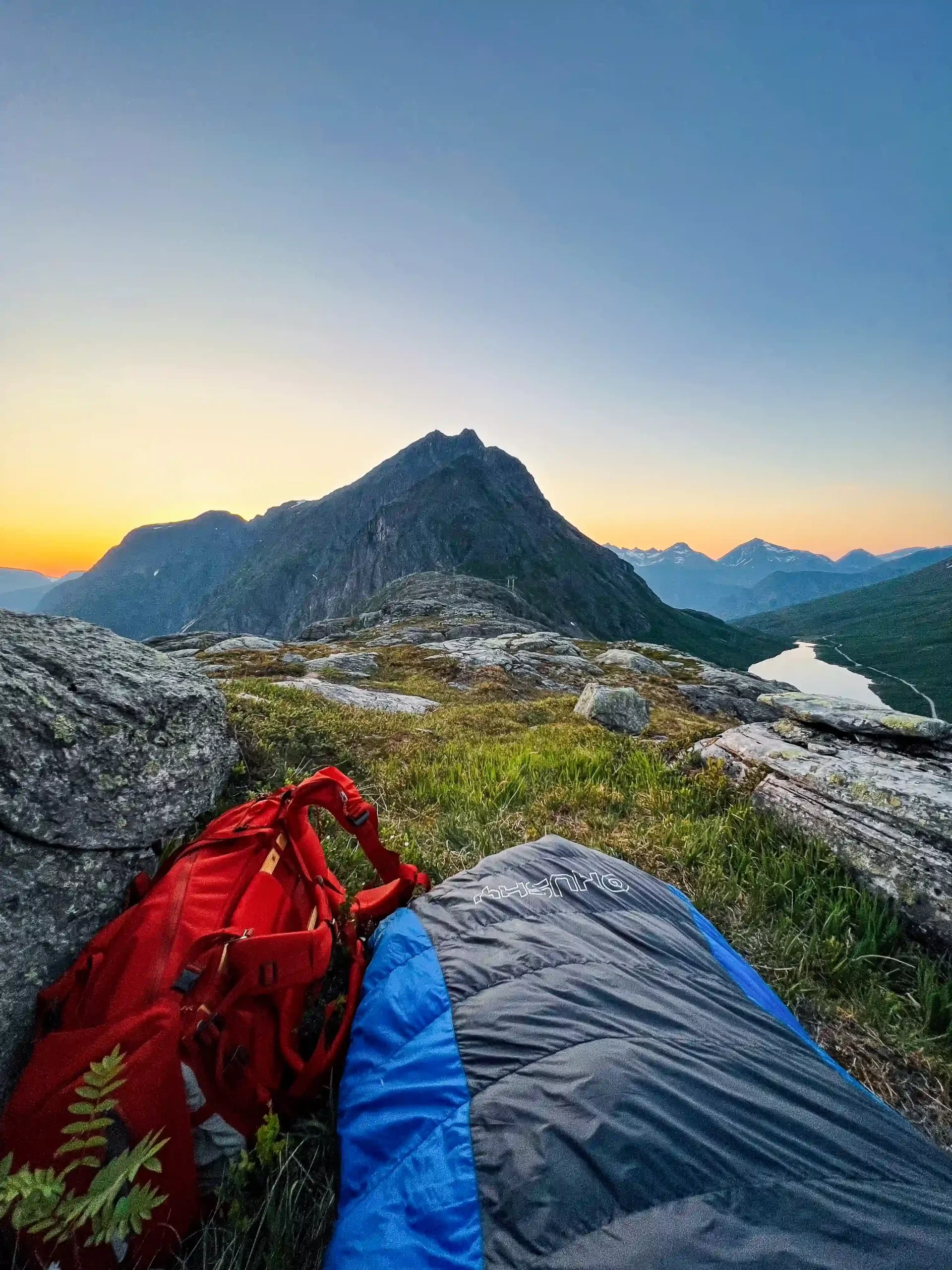 Sleeping bag and backpack above a mountain lake at sunrise in the Norwegian mountains