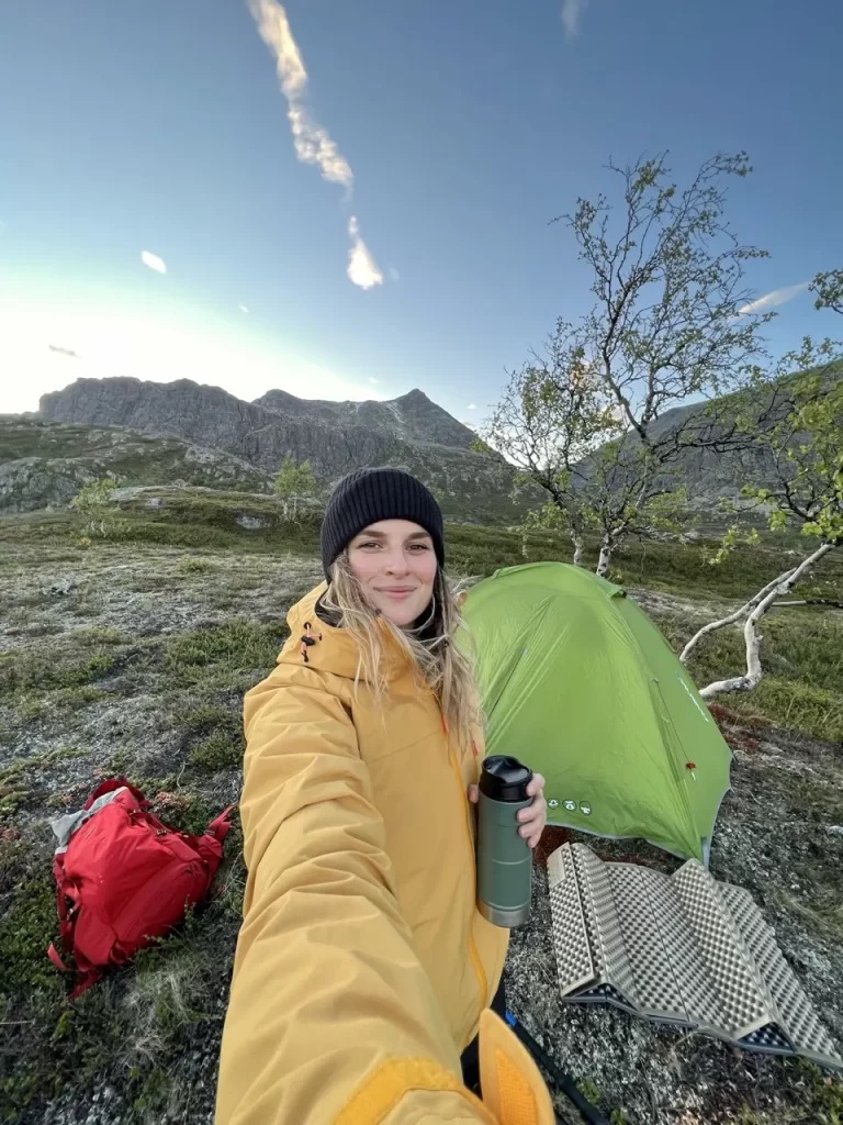 A woman standing beside a tent in open Norwegian mountain terrain, an example of utmark where the right to roam may apply.