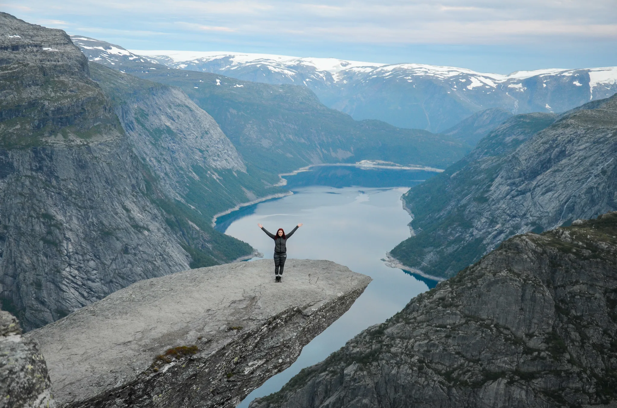 Hiker standing on Trolltunga rock above Ringedalsvatnet lake during the Trolltunga hike in Norway.