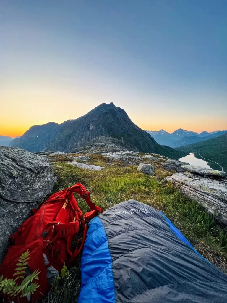 Sleeping bag and backpack on open mountain ground in Norway, showing sleeping under the stars while wild camping.