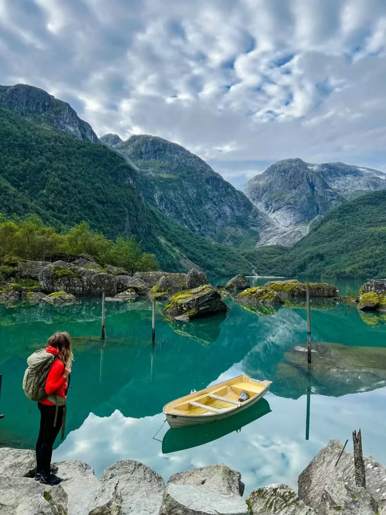 Hiker overlooking the boat and turquoise water at Bondhusvatnet lake